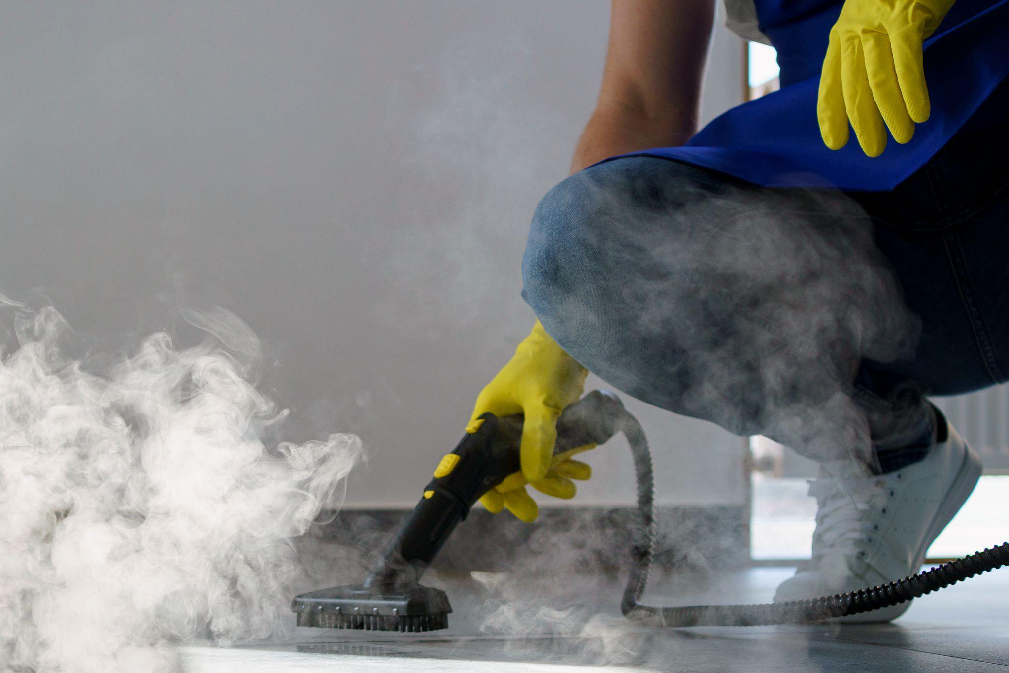 A professional cleaner using a steam cleaner on tiles