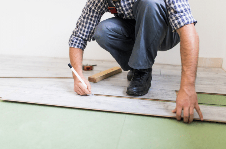 A picture of a person installing vinyl plank flooring