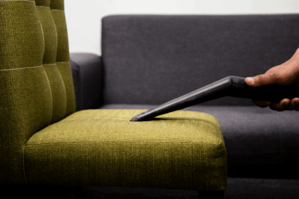 Person cleaning a sofa with a vacuum