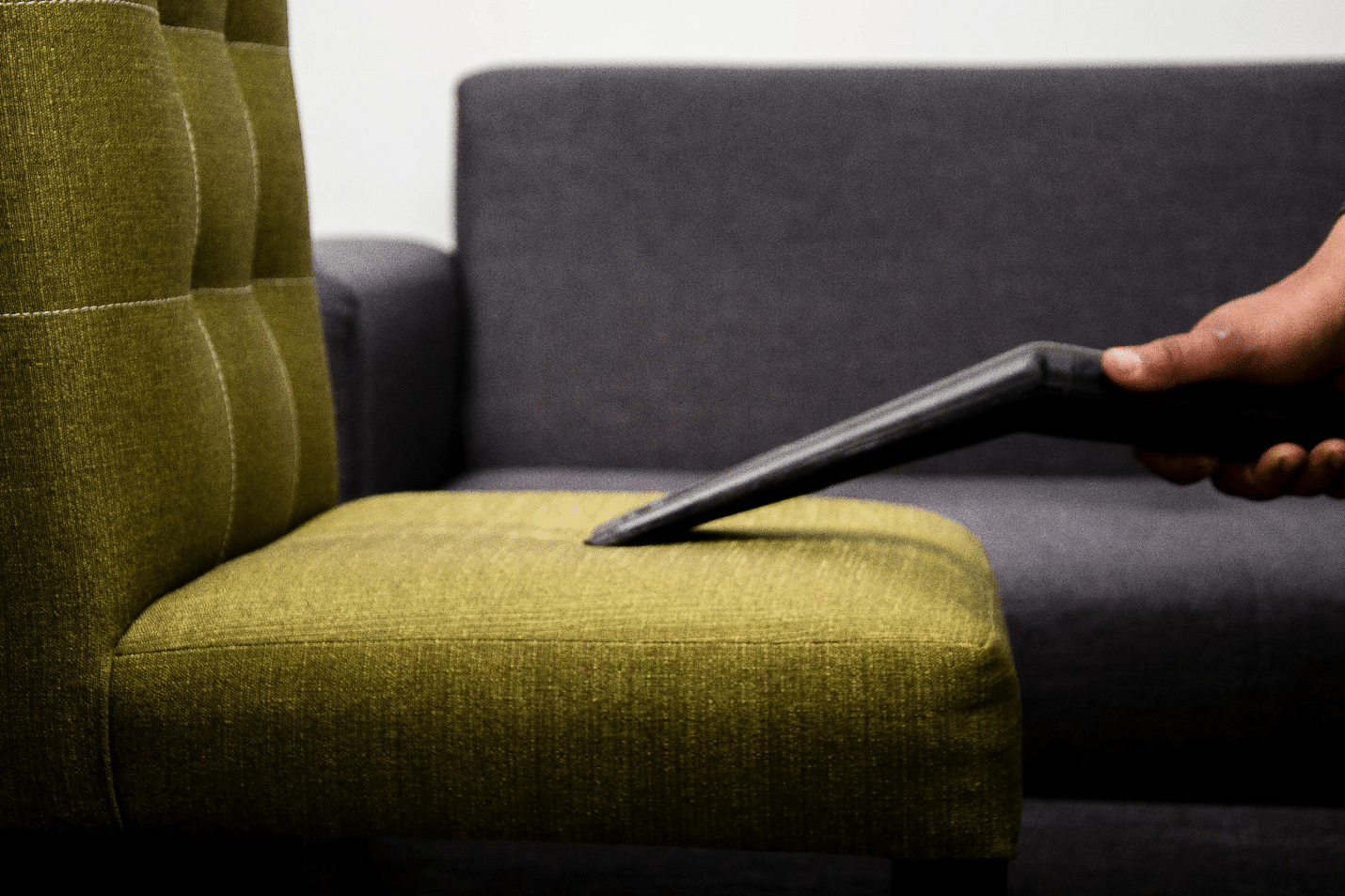 Person cleaning a sofa with a vacuum