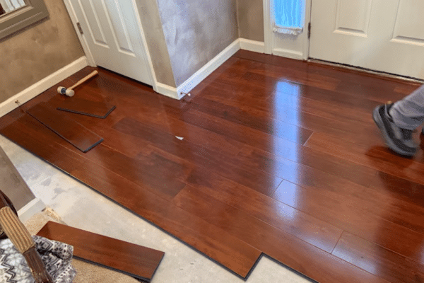 Hardwood floor planks being installed across a residential room during flooring renovation