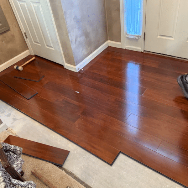 Hardwood floor planks being installed across a residential room during flooring renovation