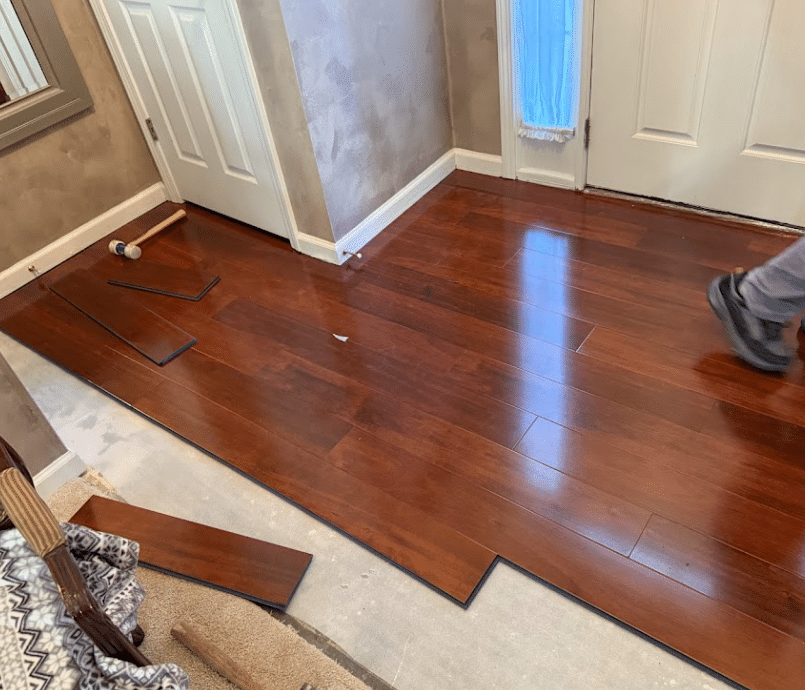 Hardwood floor planks being installed across a residential room during flooring renovation